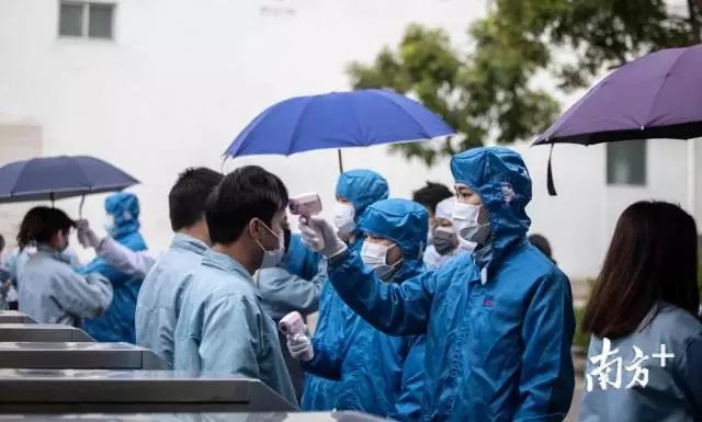进入大门的员工正在接受防疫检测。